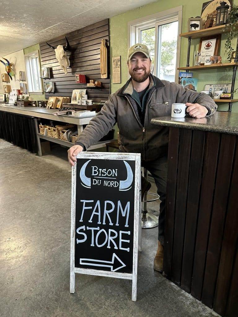 A man sitting in a farm store smiles.